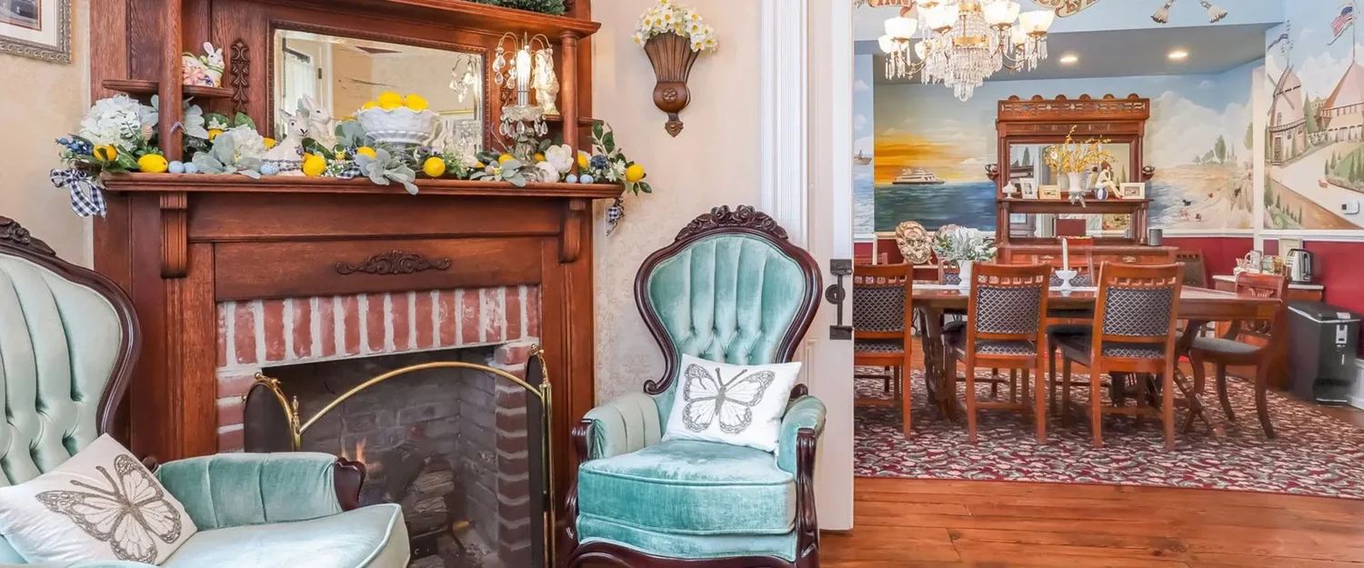 The Bedford Inn parlor and dining room with a brick fireplace and velvet armchairs