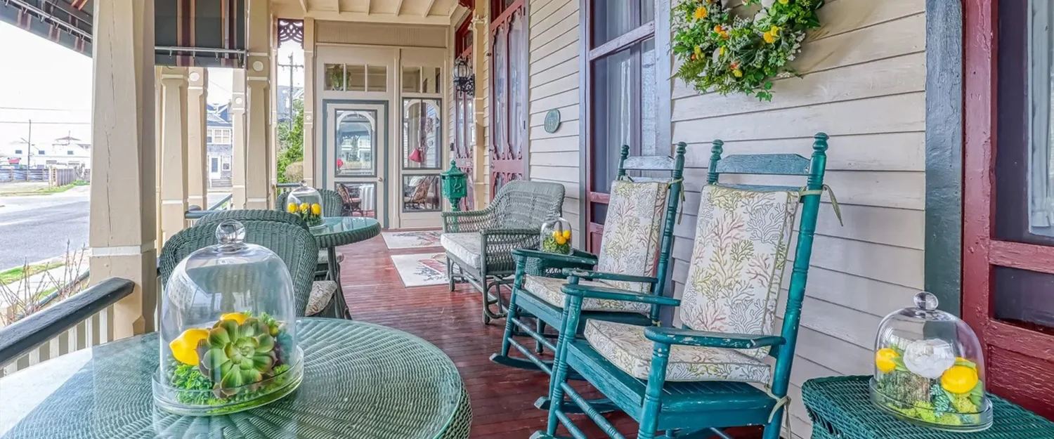 The decorated porch of Bedford Inn with rocking chairs and glass domes