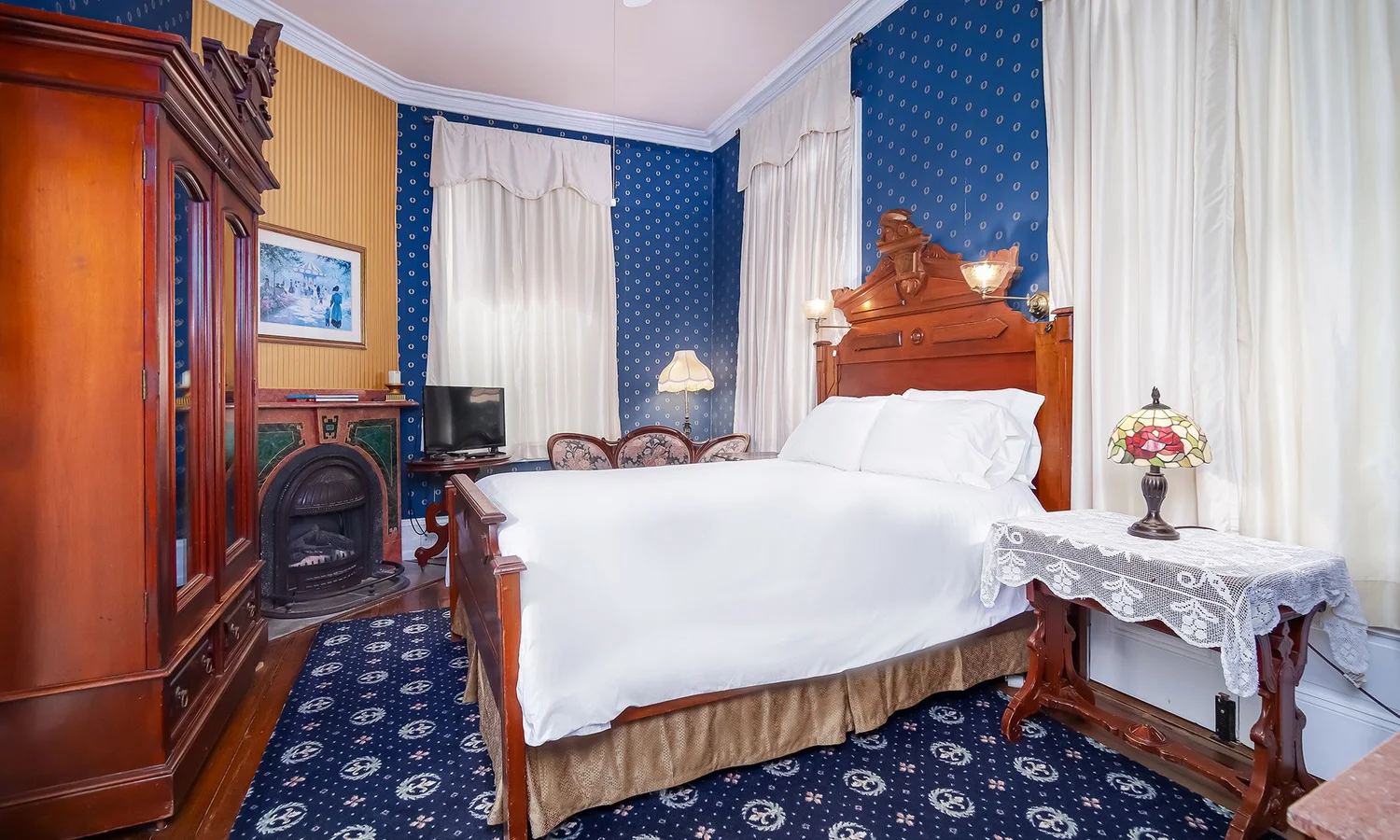 Edward's Room with blue polka-dot wallpaper, wood bed and fireplace