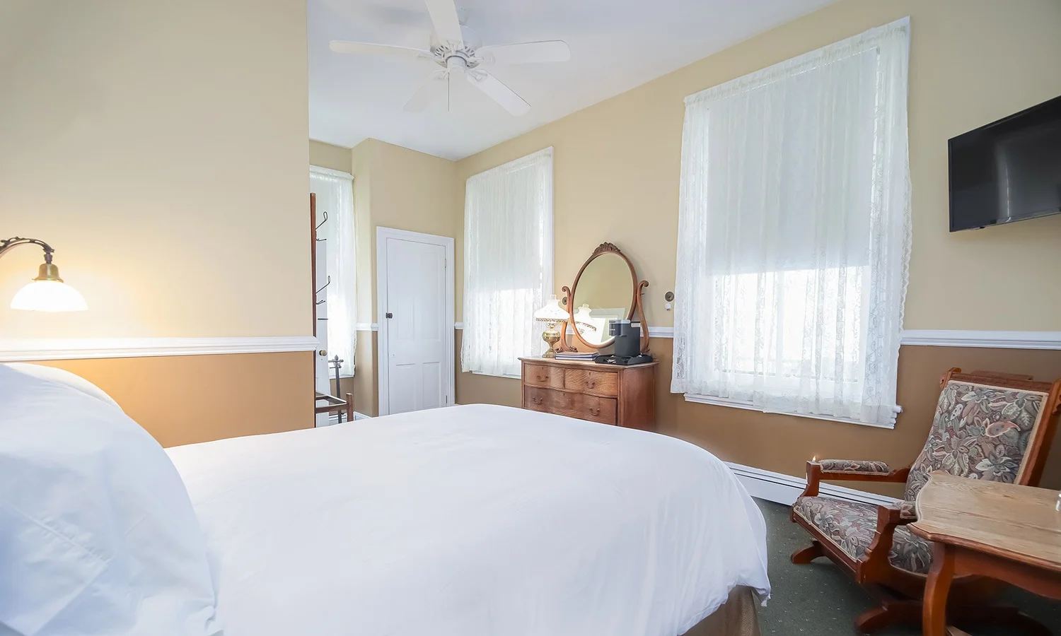 Ellie's Room with a white bed, wood dresser and floral armchair