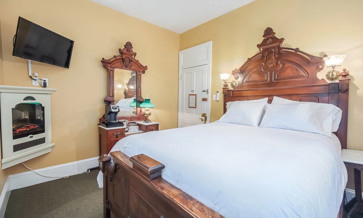 Josephine's Room with yellow walls, a carved wood bed and wall fireplace
