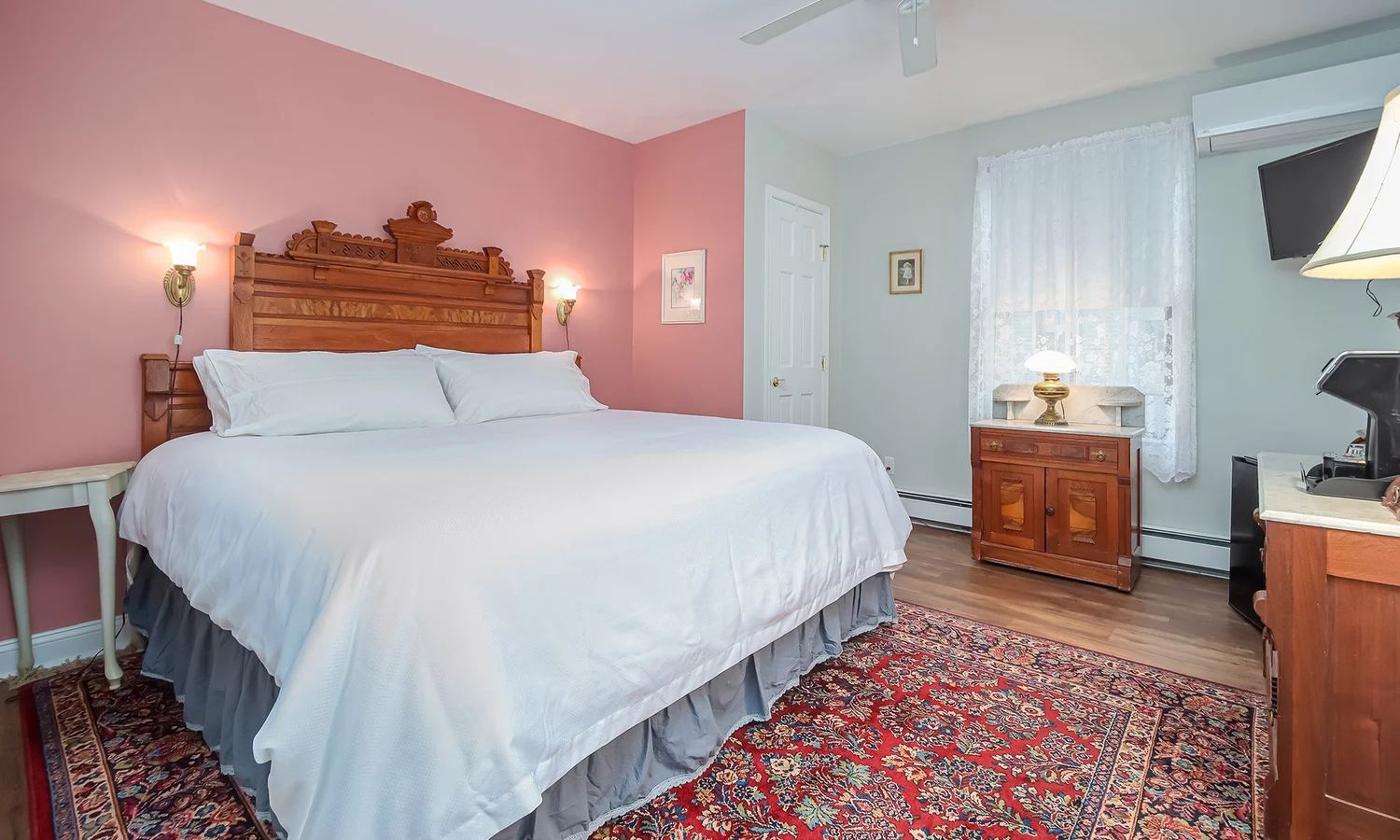 Lucinda's Suite bedroom with pink walls and a carved wood bed