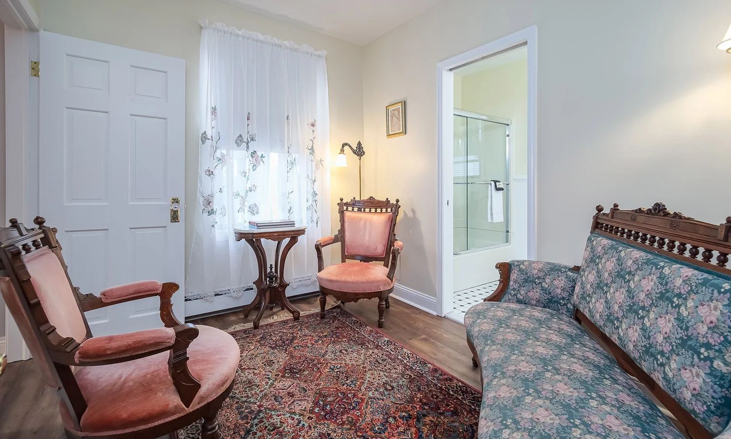 Lucinda's Suite sitting room with a pink Victorian armchair and floral loveseat